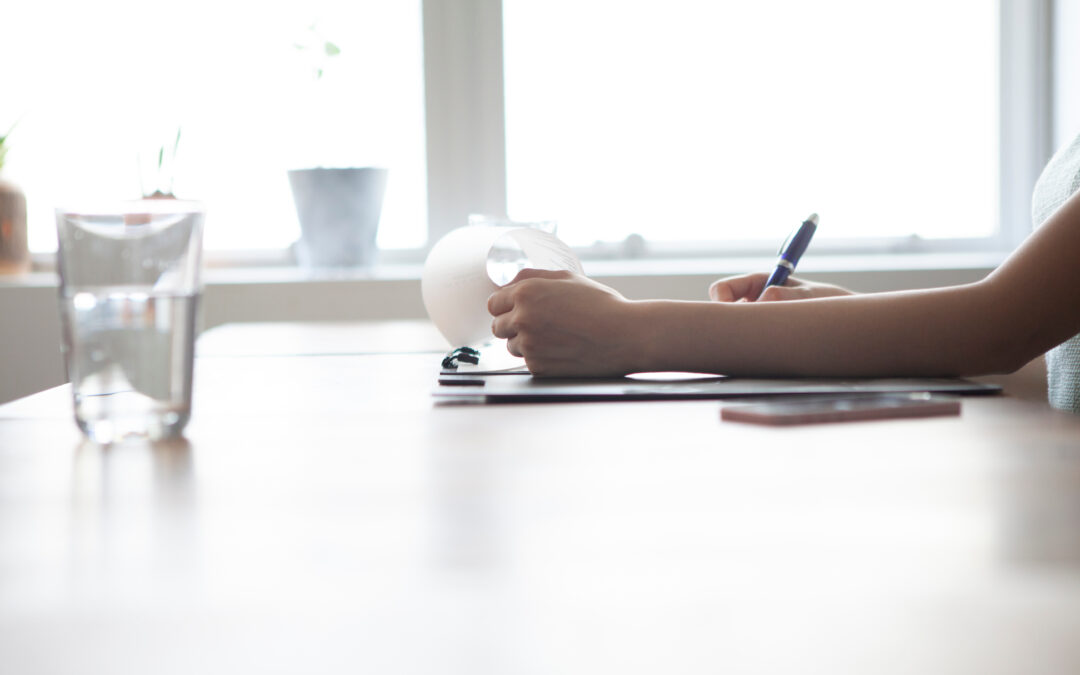 Person am arbeiten auf einem Schreibtisch neben einem Glas und einem Handy